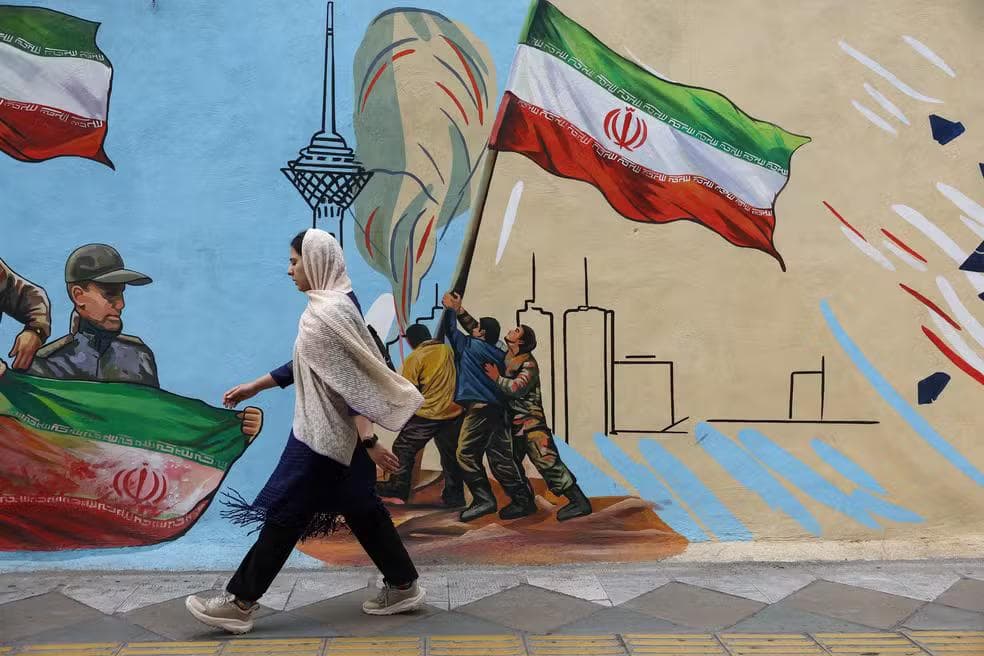 Iraniana caminha ao lado de mural com a ilustração da bandeira do Irã, em Teerã, no dia 5 de maio de 2026 — Foto: Majid Asgaripour/Wana/Reuters