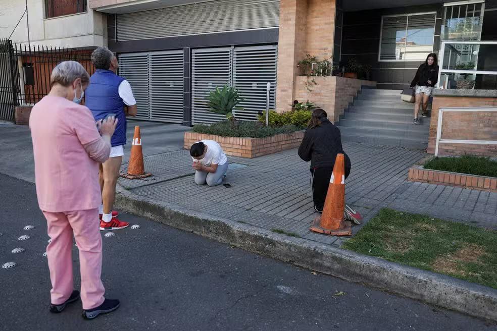Uma mulher reza enquanto pessoas se reúnem do lado de fora de um prédio após um terremoto em Bogotá — Foto: Luisa Gonzalez/Reuters