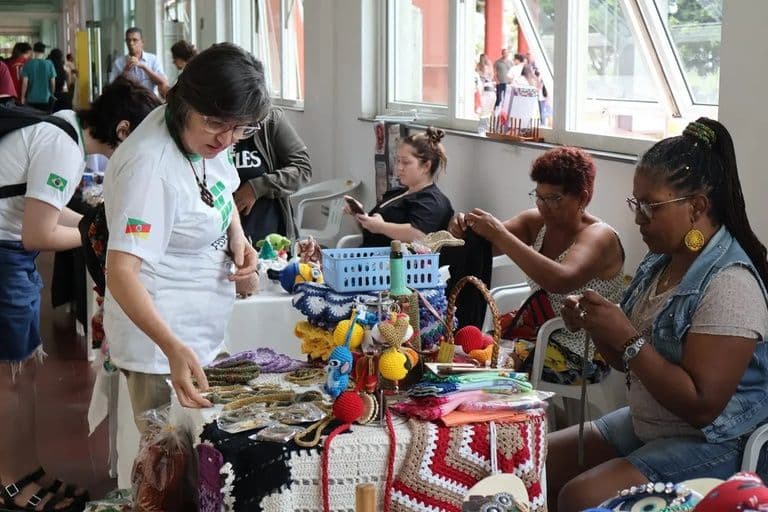 Mulheres artesãs expõem peças de crochê em uma feira de expositores. Foto: Divulgação/IFRS