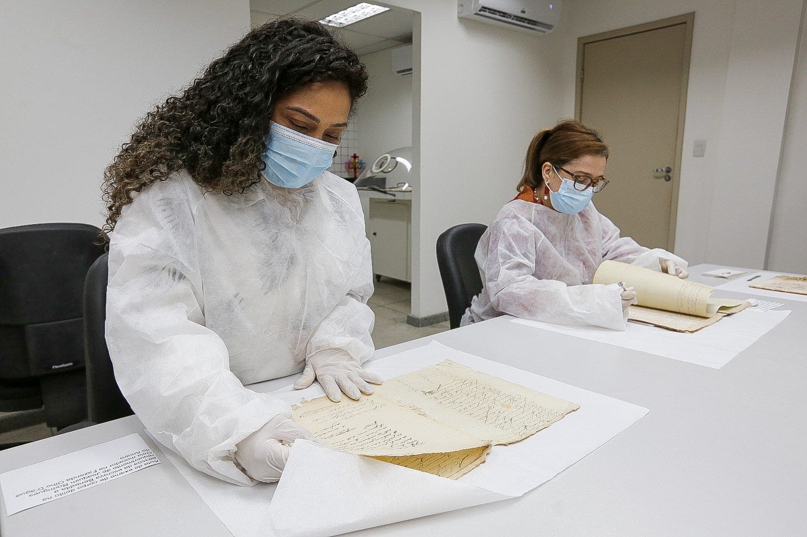 Historiadoras Mariana Marques e Hilda Monte analisam documentos que remetem ao período da escravidão em Alagoas. - Foto: Caio Loureiro