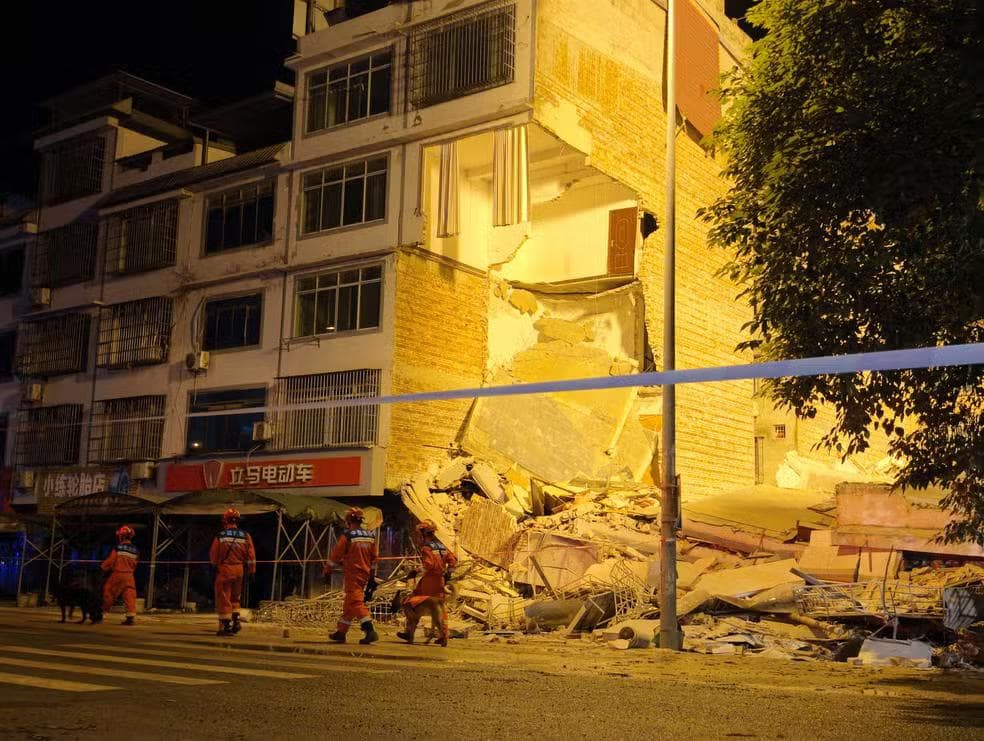 Equipes de resgate caminham ao lado de um prédio danificado após um terremoto na vila de Taiyang, em Liuzhou. — Foto: cnsphoto via Reuters