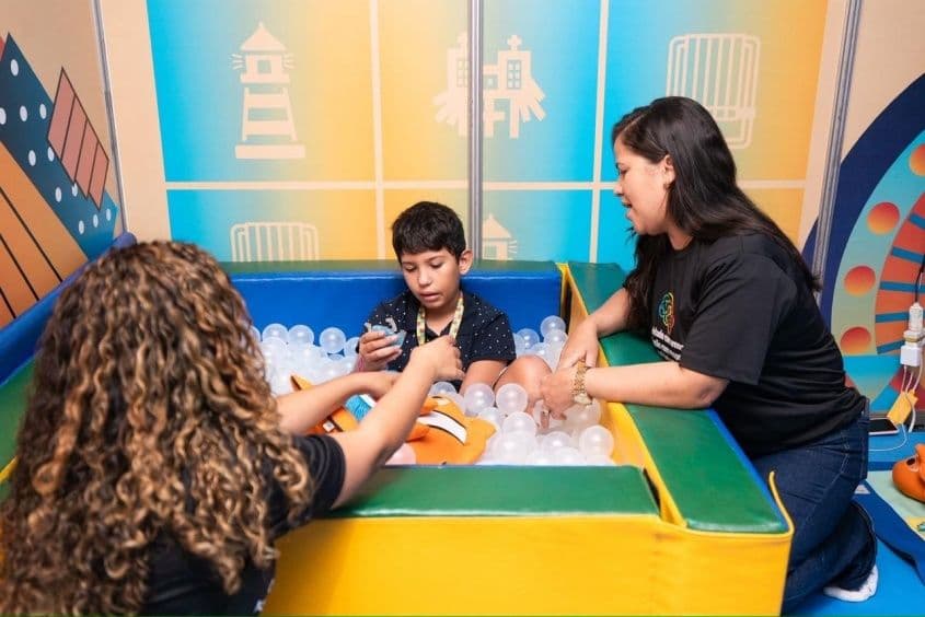Criança recebe atendimento e estímulos com recursos sensoriais na piscina de bolinhas, um dos espaços montados para acolhimento e acomodação durante o evento. Foto: Victor Vercant/Secom Maceió